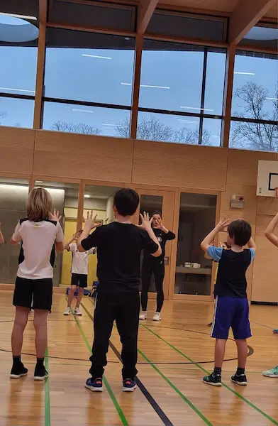 Kinder üben in der Turnhalle das Pritschen
