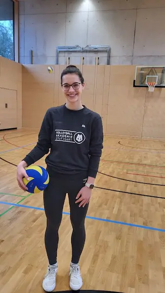 Die Volleyballtrainerin mit einem Ball in der Turnhalle