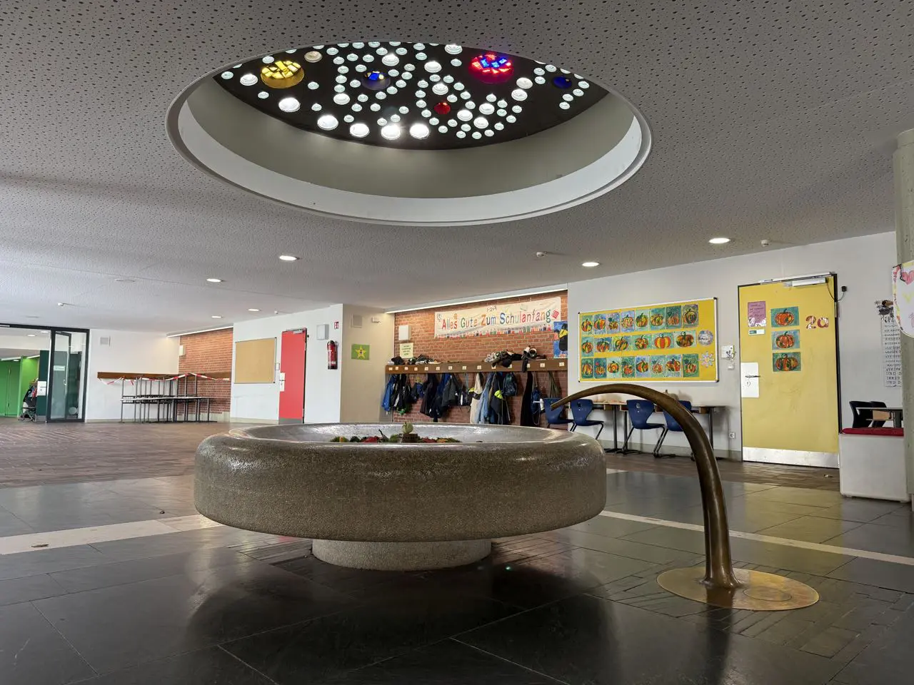 Der runde Schulbrunnen unter dem Oberlicht im Foyer