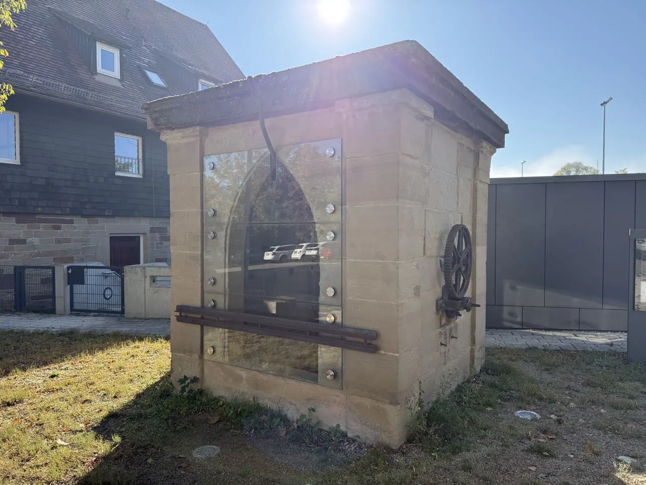 Das alte Brunnenhaus aus Sandstein mit Glasfront und Rad