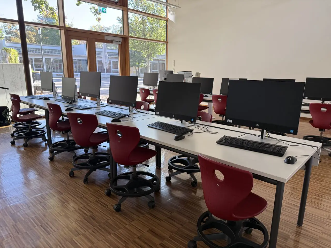 Computerraum mit Bildschirmen und roten Stühlen