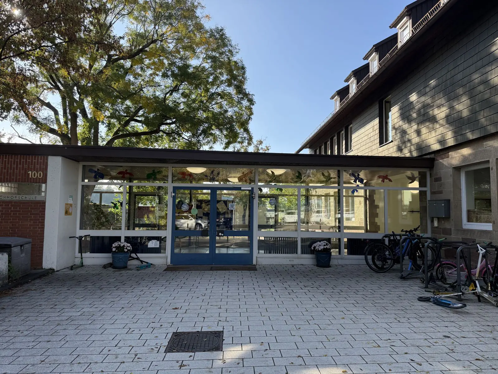 Haupteingang der Schule mit Glastür und Fahrradständern