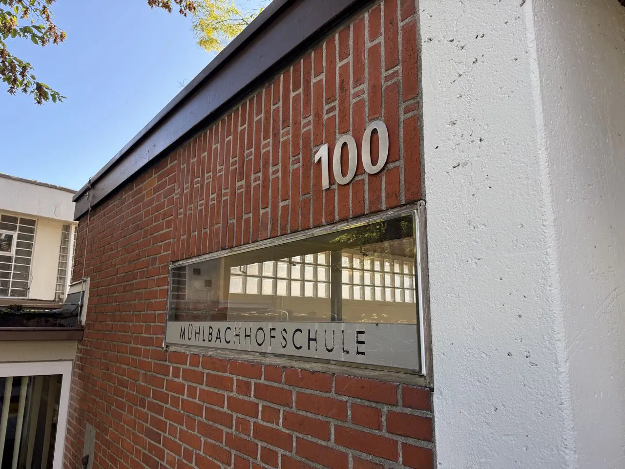 Backsteinfassade mit der Hausnummer 100 und dem Schulnamen