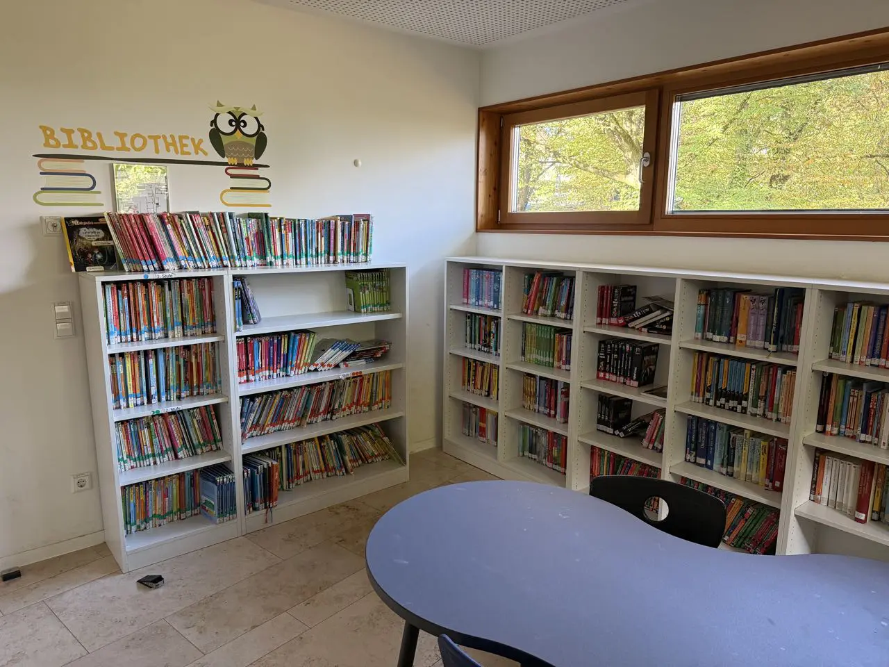 Schulbücherei mit Bücherregalen und einem runden Tisch