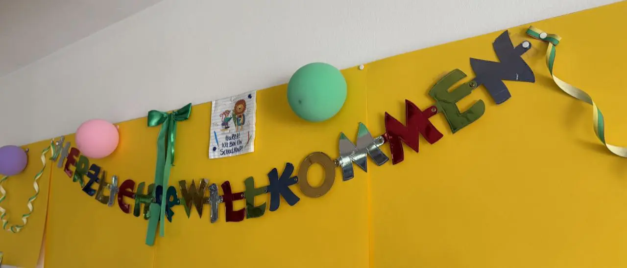 Girlande „Herzlich willkommen“ an einer gelben Wand im Klassenzimmer